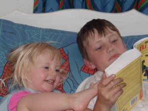 big brother conor reading to little sister layla, caught in the act of reading, http://PragmaticMom.com, pragmatic mom