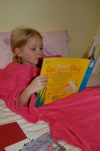 caught in the act of reading, http://Pragmaticmom.com, girls sisters reading in snugglies