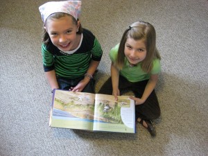 Fourth grader Eva J and first grader Julia C read A Place for Birds, caught in the act of reading, http://PragmaticMom.com
