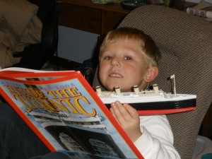Kevin reading about and holding Titantic, caught in the act ... of Reading, http://PragmaticMom.com, PragmaticMom