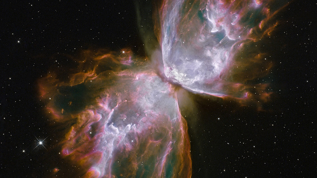 What resemble dainty butterfly wings are actually roiling cauldrons of gas heated to more than 36,000 degrees Fahrenheit. The gas is tearing across space at more than 600,000 miles an hour—fast enough to travel from Earth to the Moon in 24 minutes. A dying star is at the center of this fury. It has ejected its envelope of gases and is now unleashing a stream of ultraviolet radiation that is making the cast-off material glow.