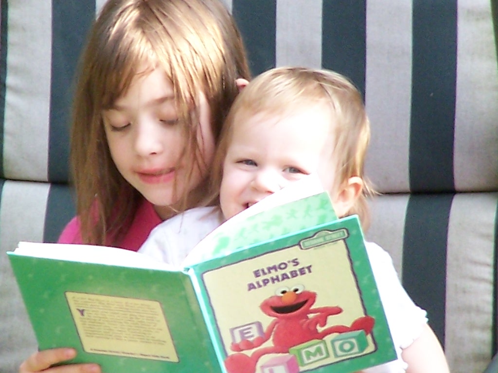 reading to little sister, caught in the act of reading, http://PragmaticMom.com